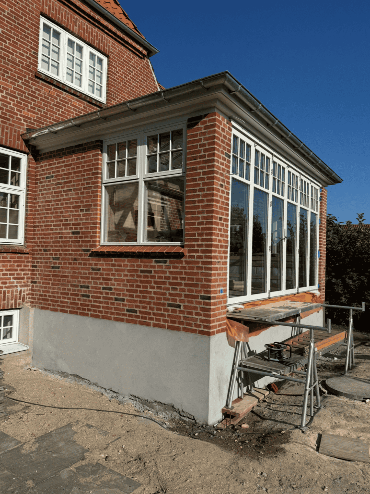 Renoveret rød murstensfacade med havestue