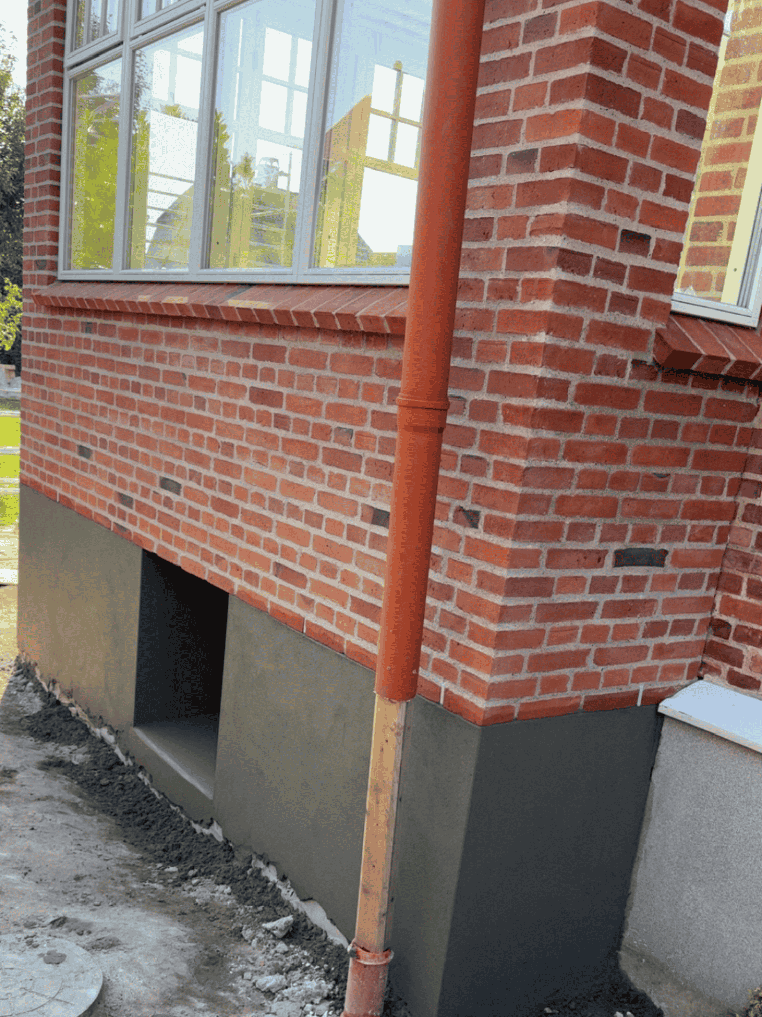 Detalje af røde mursten ved facade med nedløbsrør